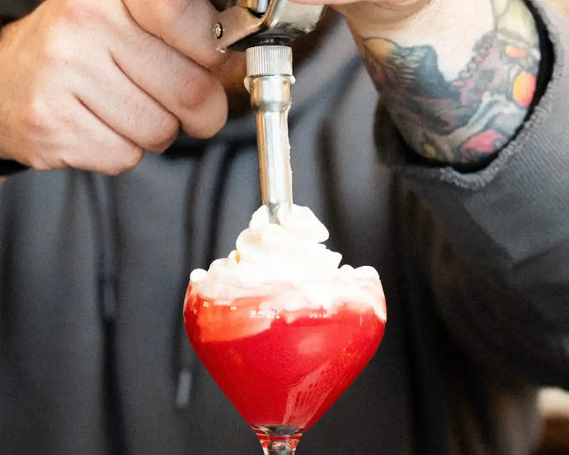Cocktail with savory tomato foam and dehydrated orange slice garnish