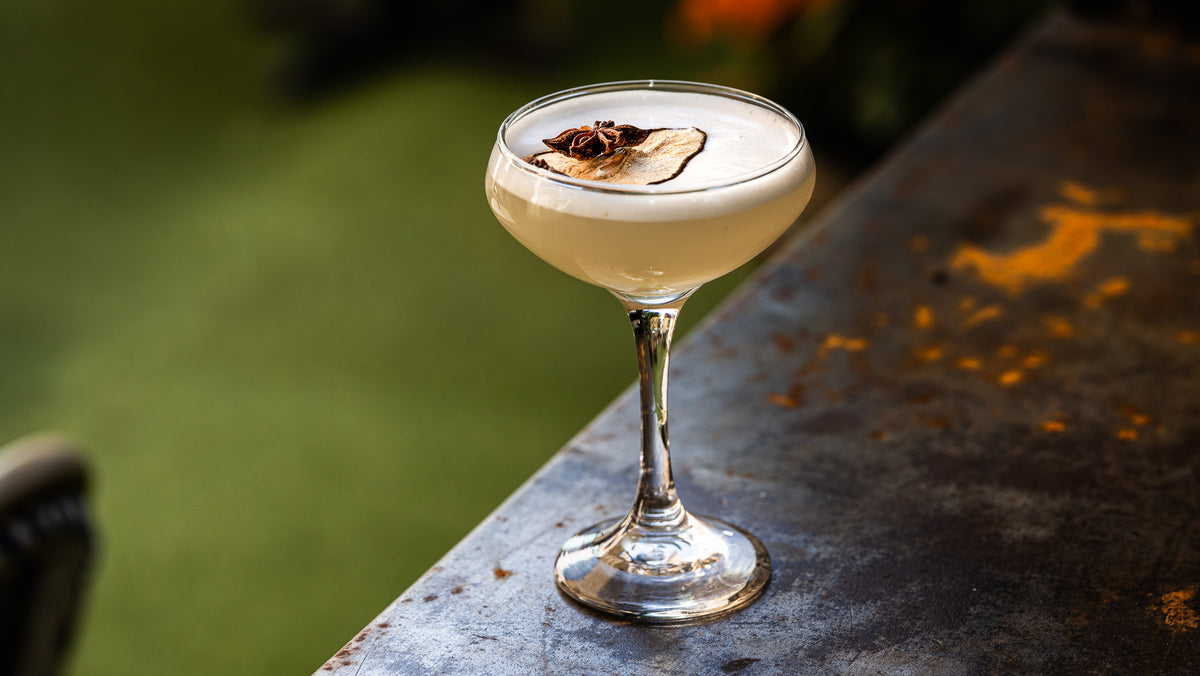 Coupe glass martini with pear garnish floating and star anise sitting on top.