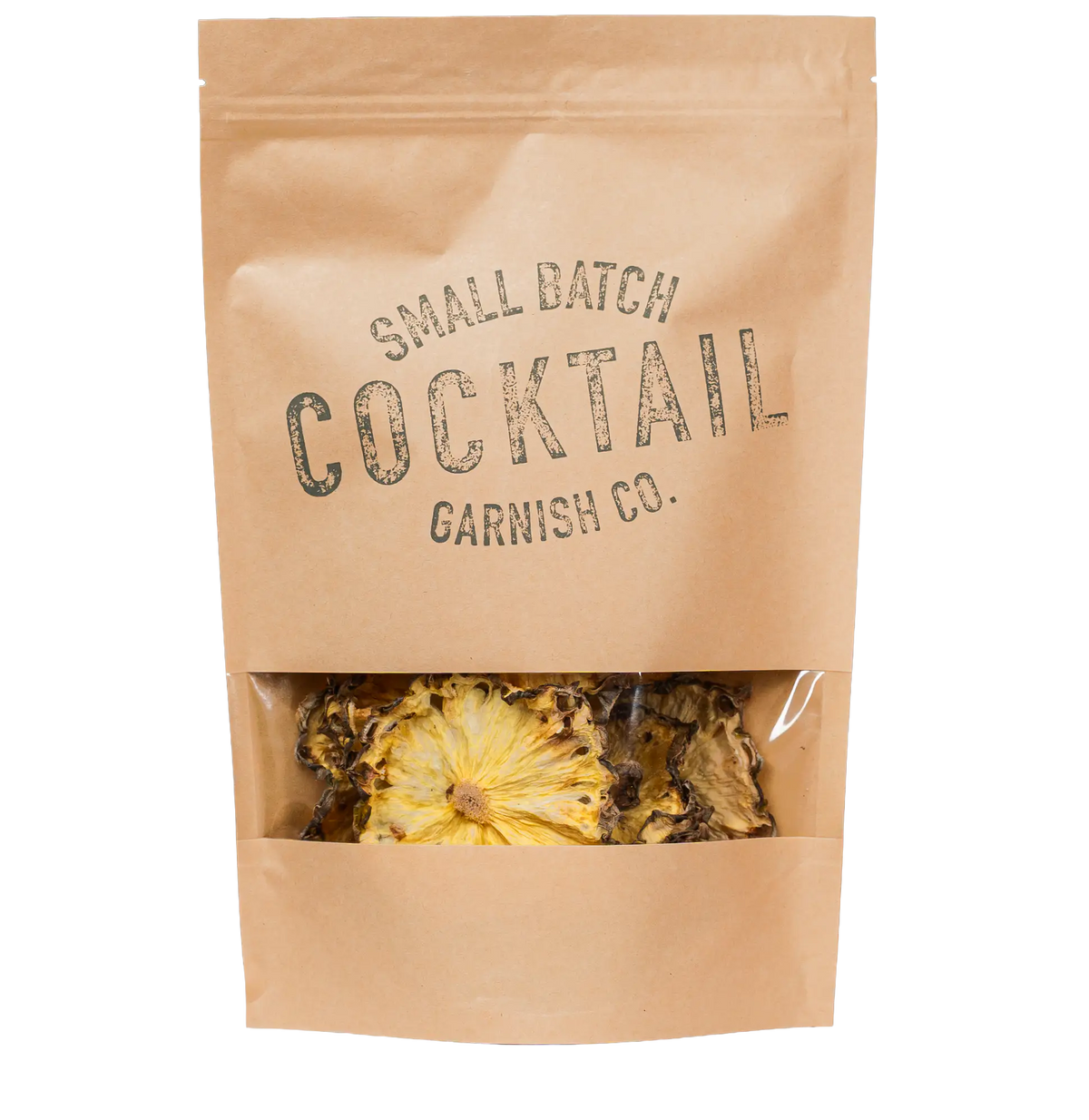 A kraft paper stand-up pouch of dried pineapples with a clear window near the bottom, showing dried cocktail garnish inside. The pouch is printed with the text 'SMALL BATCH COCKTAIL GARNISH CO.