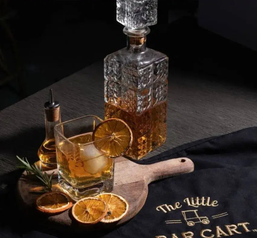 A whiskey canter and dried orange slices from cocktail garnish co. in a square rocks glass with a large cube and whiskey