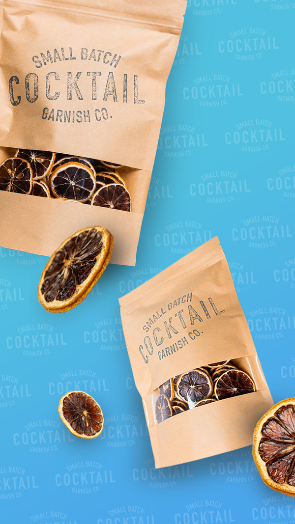 Falling dehydrated cocktail garnish co lemon bags on a blue background with large individual lemon slices floating