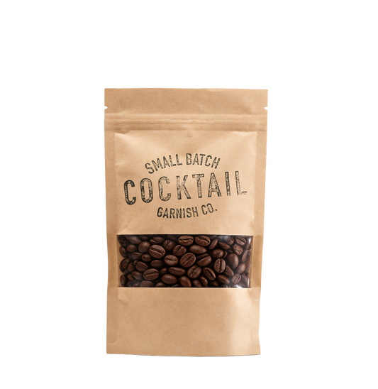 A kraft paper stand-up pouch of Garnish Co. 'Small Batch Cocktail' coffee beans, featuring a clear window displaying the dark roasted coffee beans inside, set against a plain white background.