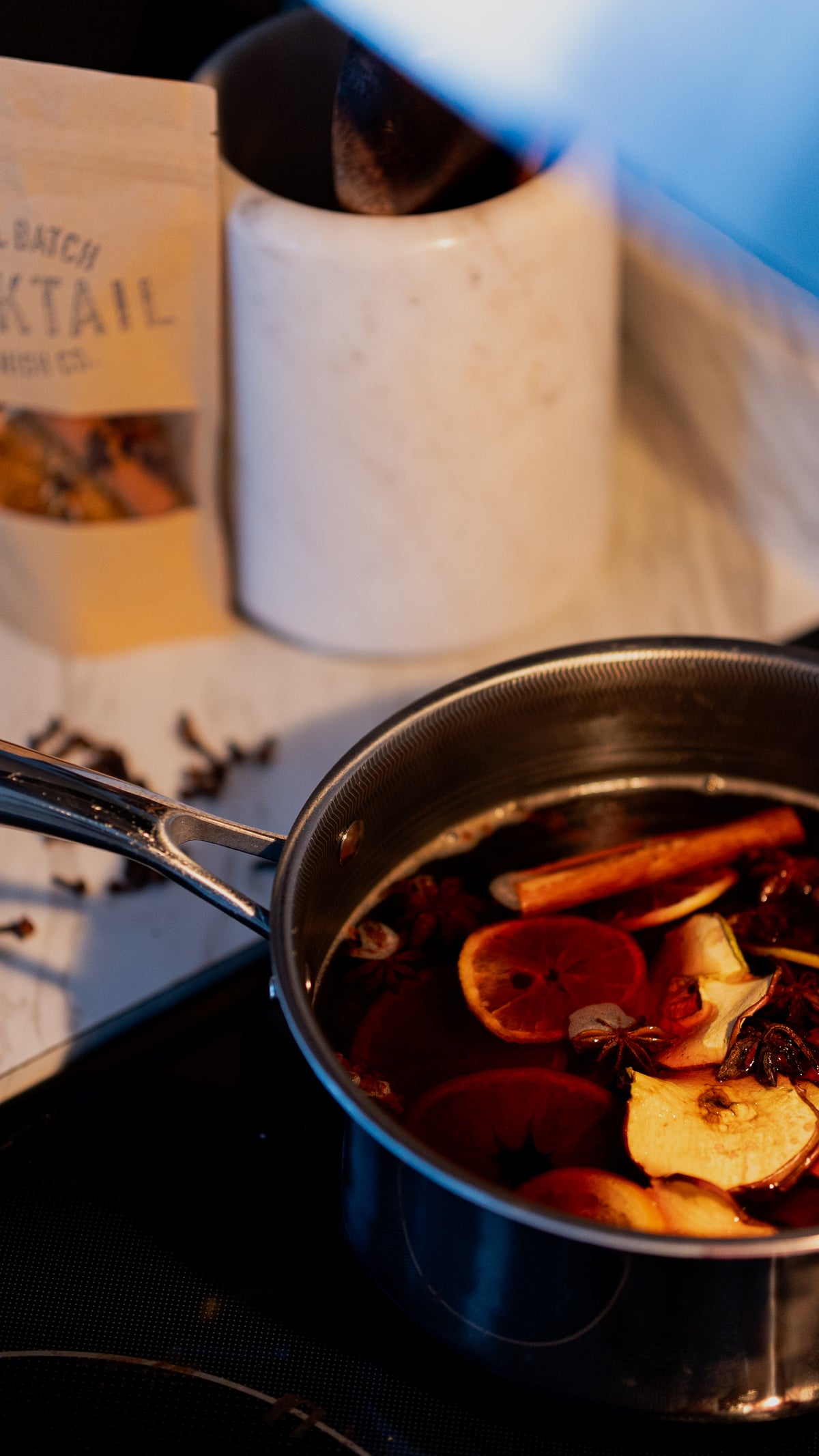 Mulled wine in pot on stove with cinnamon orange apple star anise and clove