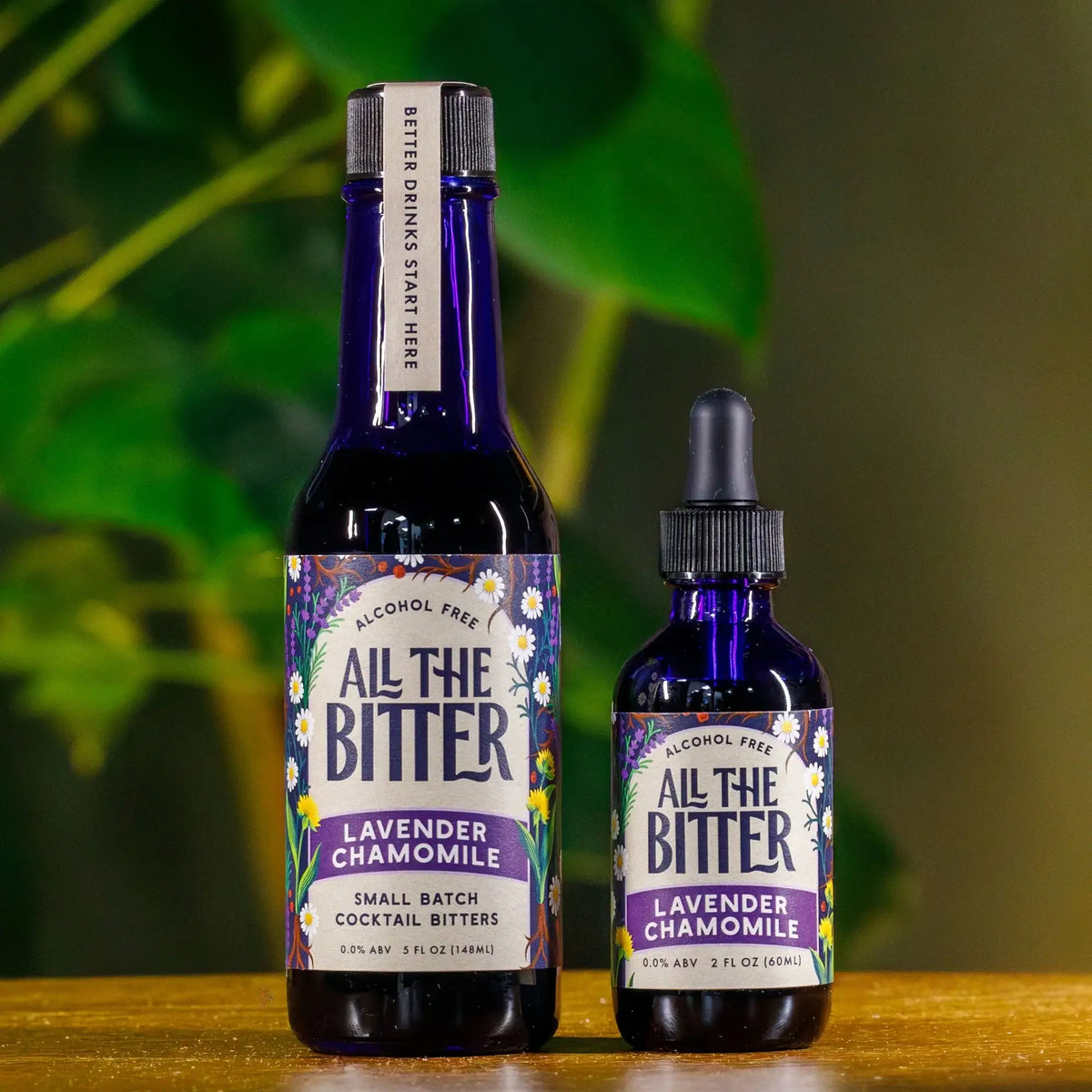 All The Bitter Lavender Chamomile alcohol-free cocktail bitters in 5 oz bottle and 2 oz dropper bottle against green foliage